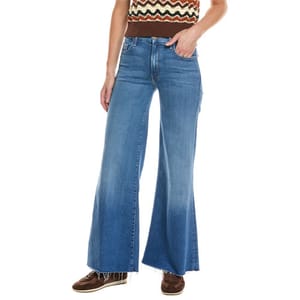 Flared blue jeans with frayed hems, paired with brown shoes and worn by a person in a brown and cream patterned top.