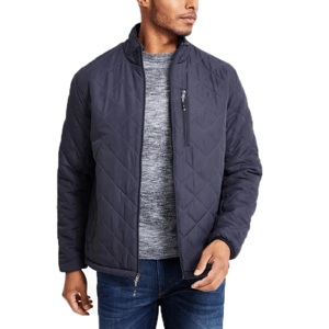 A man is wearing a dark quilted jacket with a zip-up design, over a gray sweater and blue jeans. The jacket features a chest zipper pocket and a high collar.