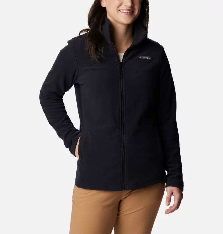 A woman wears a black full-zip fleece jacket and khaki pants.
