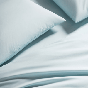 Light blue pillowcases and bedsheets are shown, emphasizing a smooth and soft texture.