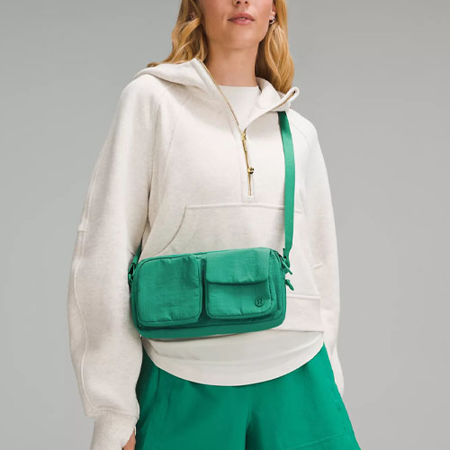A woman wearing a white hoodie and green skirt with a green crossbody bag.