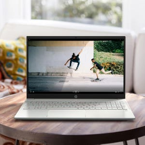 A silver HP laptop displaying a video of two people skateboarding.