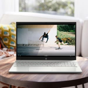 A silver HP laptop displaying a video of two people skateboarding.