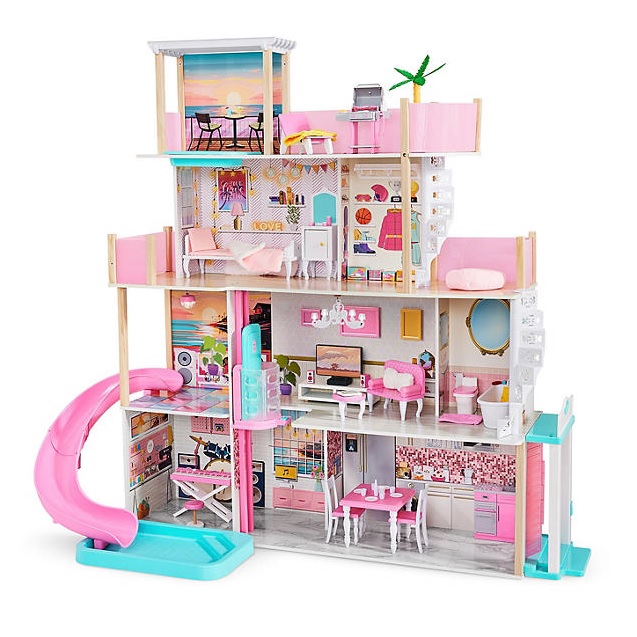 This is a large, multi-story wooden dollhouse with pink and blue accents, featuring a variety of furnished rooms and an exterior slide. It includes a kitchen, bedroom, bathroom, dining area, and outdoor patio.