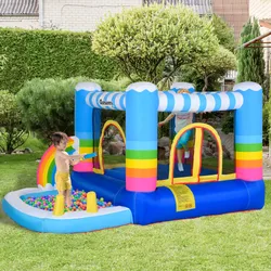 Inflatable bounce house with a rainbow theme, featuring a ball pit area, set up in a garden with children playing.
