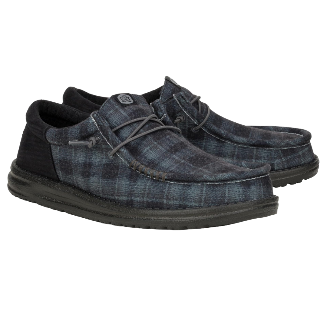 Hey Dude Wally Funk Shoes feature a soft checked plaid fabric in blue and black, with a moccasin-style design and lightweight sole for casual comfort.