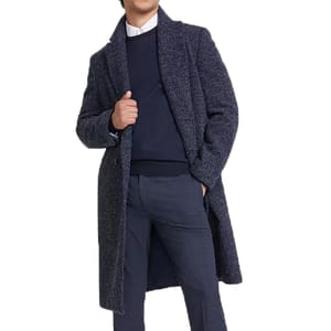 A person is wearing a long, textured navy overcoat over a dark sweater, a white shirt, and blue pants.