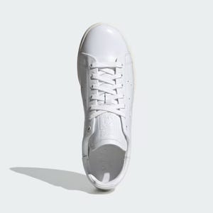 White low-top leather sneaker with laces, perforated stripes on the side, and embossed logo on the tongue and heel tab.