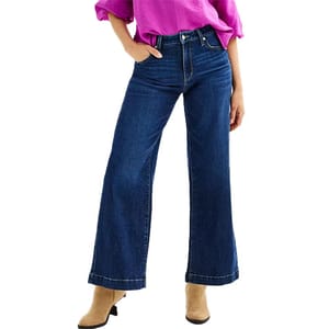 Woman wearing blue wide-leg jeans and a purple top, paired with beige shoes.