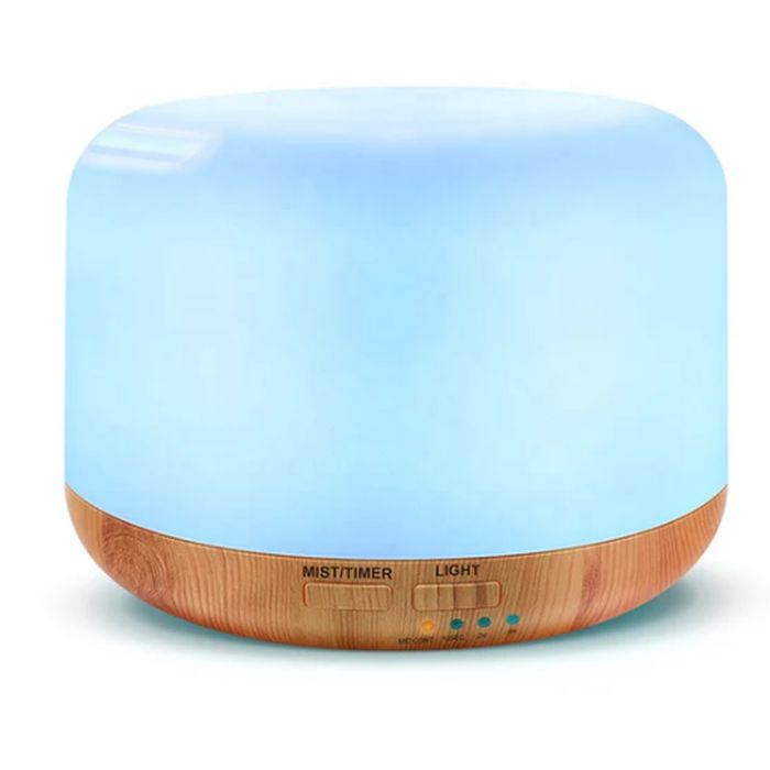 A round essential oil diffuser with a light wood base and glowing blue top, featuring controls for mist, timer, and light settings.