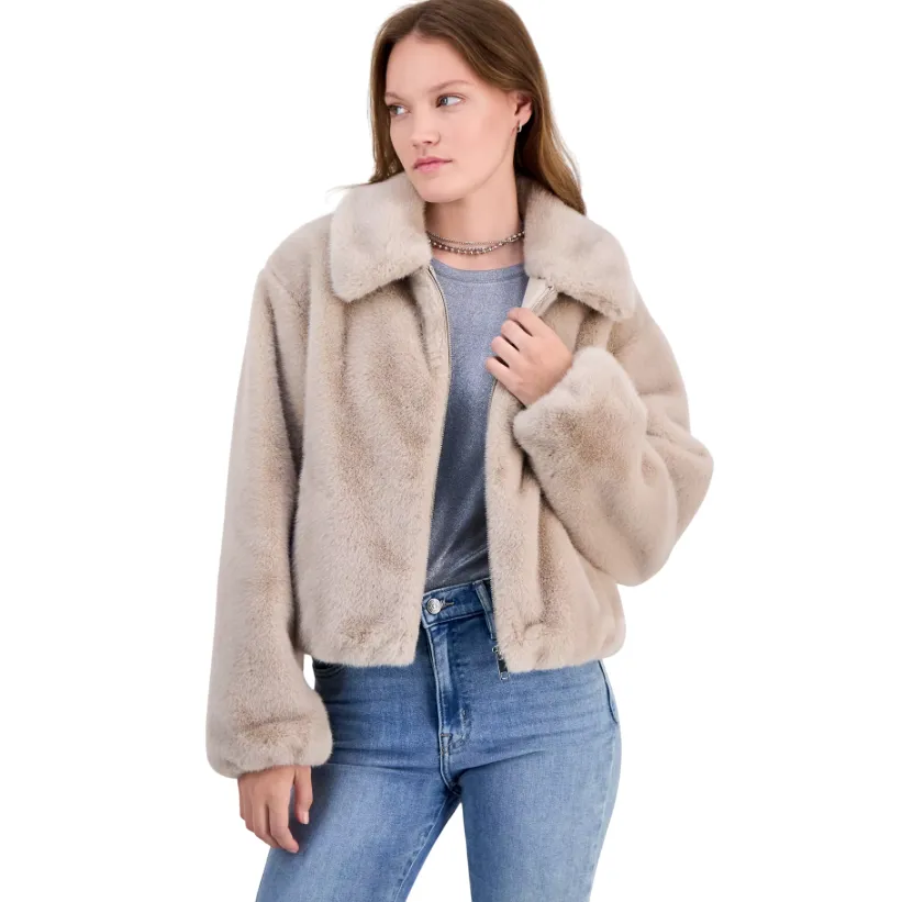A woman is wearing a light beige faux fur jacket over a gray top paired with blue jeans.