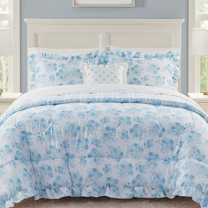 A blue and white floral patterned bed set consisting of a comforter, pillowcases, and a decorative cushion.