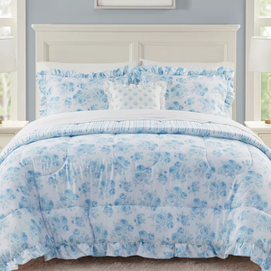 A blue and white floral patterned bed set consisting of a comforter, pillowcases, and a decorative cushion.