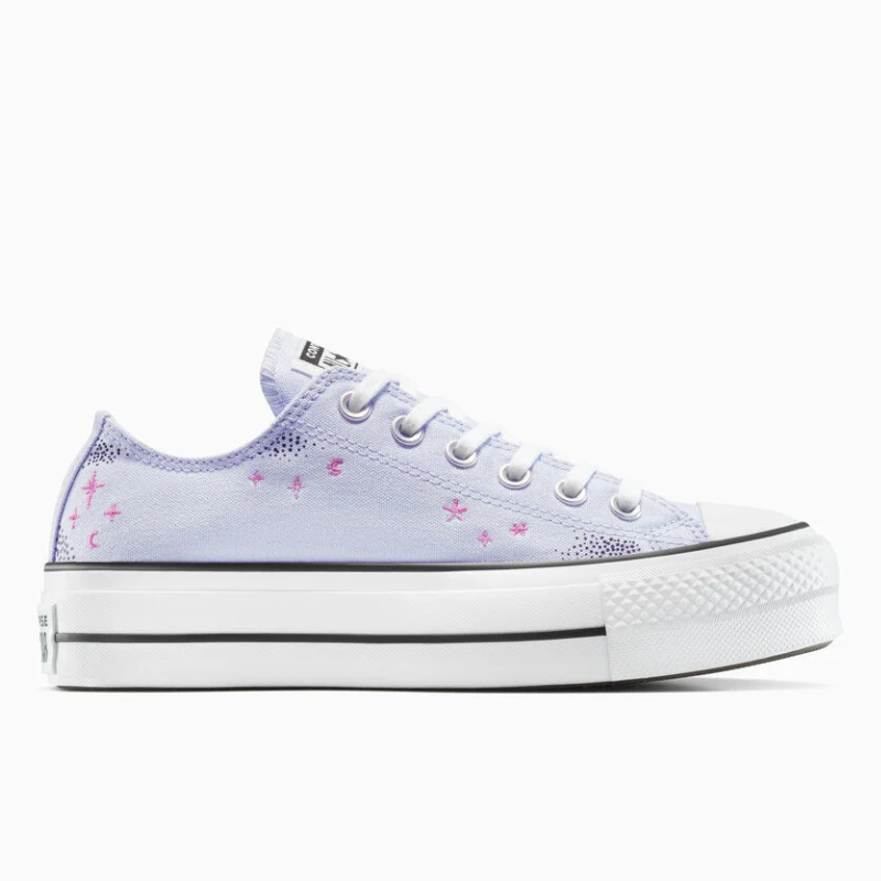 A lavender low-top sneaker with a platform sole, featuring pink star and moon designs on the side, and classic white laces.