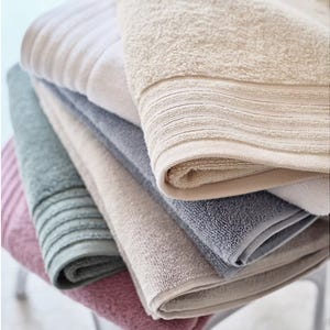 A stack of folded towels in various colors including beige, gray, green, and maroon.