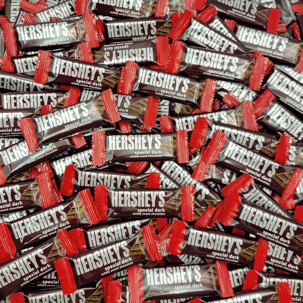 Hershey's Special Dark mildly sweet chocolate bars with red wrappers are displayed in a large pile.
