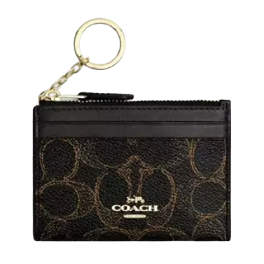 A Coach cardholder with a gold-toned keyring, featuring the brand's signature pattern and logo on a dark background.