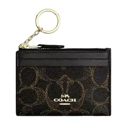 A Coach cardholder with a gold-toned keyring, featuring the brand's signature pattern and logo on a dark background.