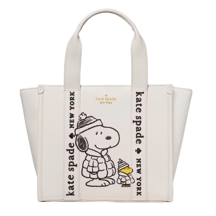 A white Kate Spade New York tote bag featuring Snoopy and Woodstock in winter attire, with \“kate spade new york\“ text on the straps.