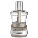 A metallic food processor with a clear plastic bowl and lid, featuring controls for low, high, and pulse settings.
