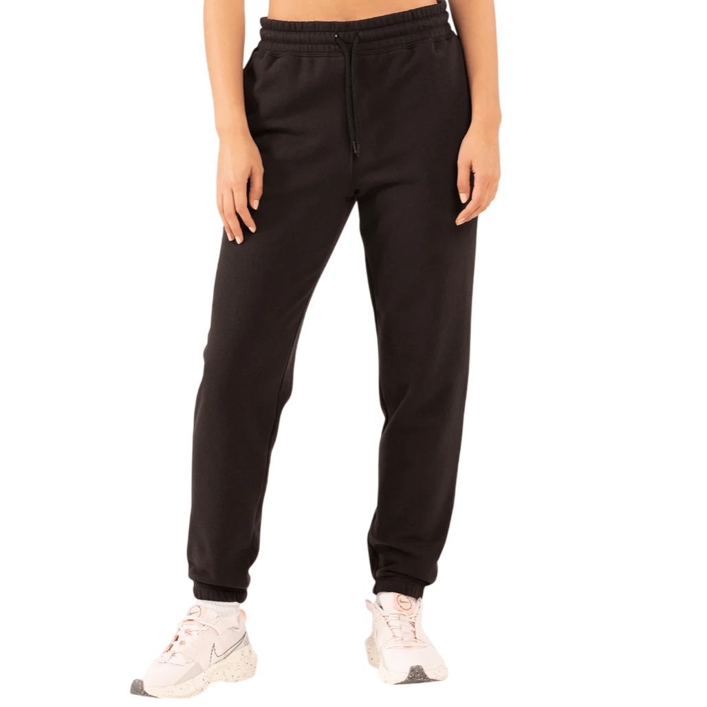 Black jogger pants with an elastic waistband and drawstring, paired with white sneakers featuring pink accents.