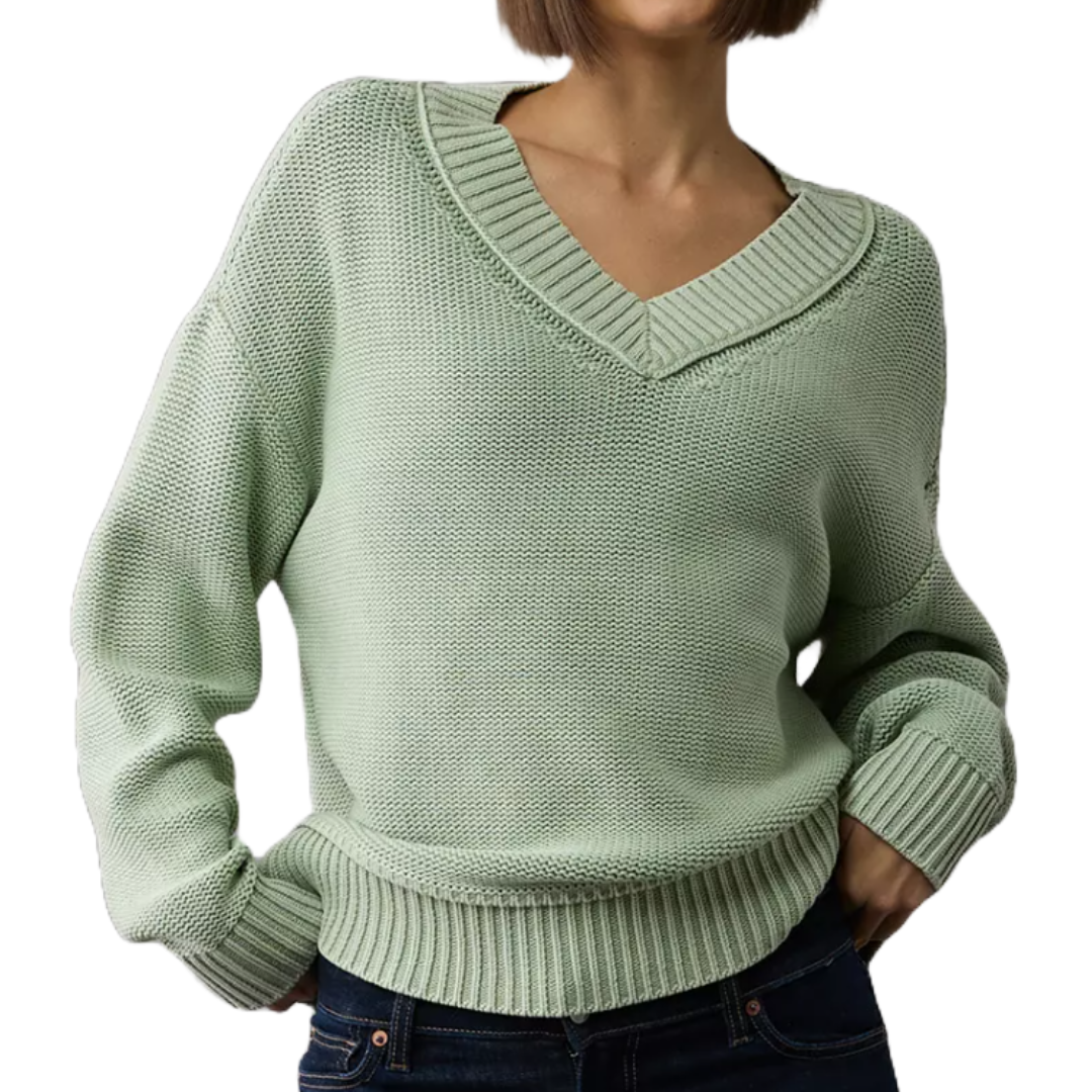 A light green V-neck knit sweater with ribbed cuffs and hem, paired with dark jeans.