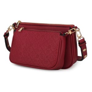 A red 2-piece shoulder bag set featuring embossed patterns, gold-toned hardware, and adjustable straps with button details.