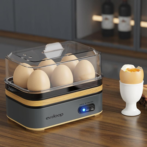 Electric egg cooker with timer, auto-stop heat, and multi-function features, holding six eggs. An egg cup with a soft-boiled egg and a sliced avocado are placed nearby.
