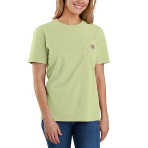 A woman is wearing a light green Carhartt T-shirt with a pocket logo on the chest, paired with blue jeans.
