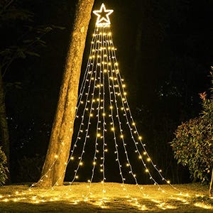 A string of LED lights creates the silhouette of a Christmas tree with a lit star on top, attached to a tree and extending to the ground.