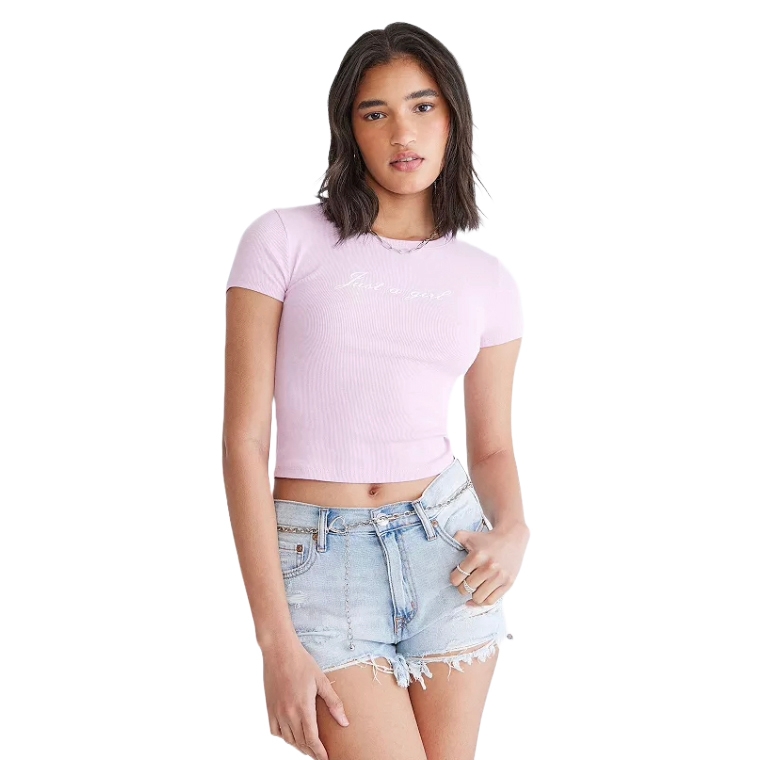 A woman is wearing a light pink short-sleeve crop top and light blue denim shorts.