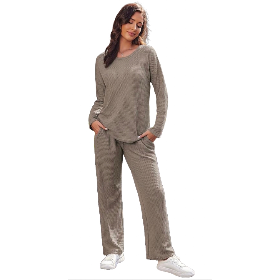 A woman is wearing a taupe long-sleeve top with matching wide-leg pants made of a soft, textured fabric, paired with white sneakers. The outfit reflects a comfortable and casual loungewear style.