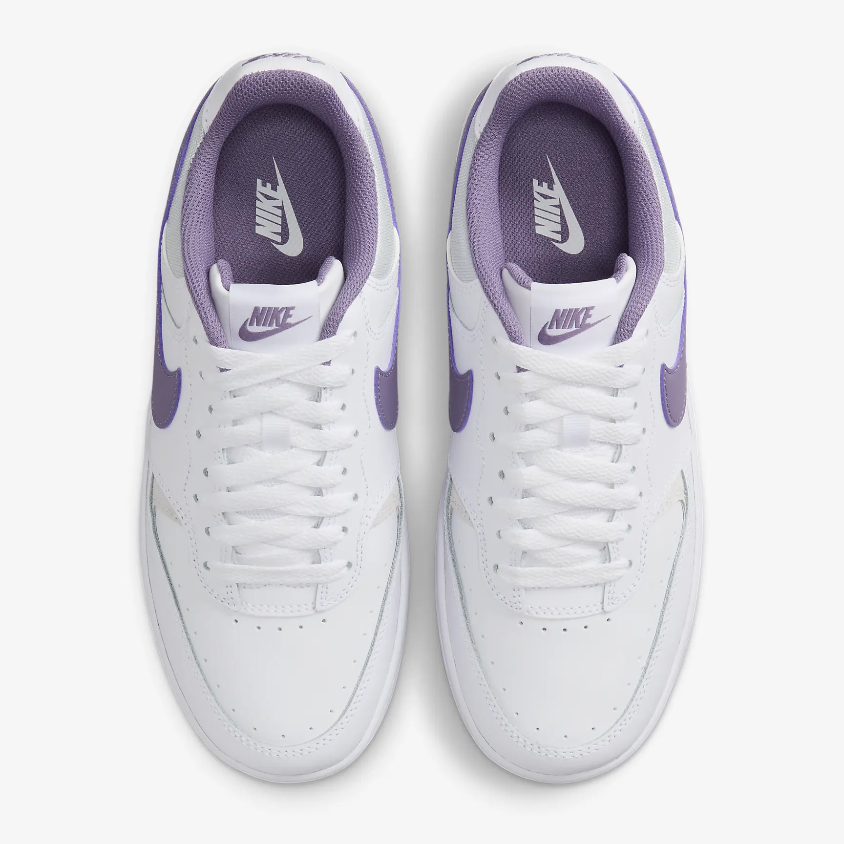 A pair of white sneakers with purple accents and laces, viewed from above.