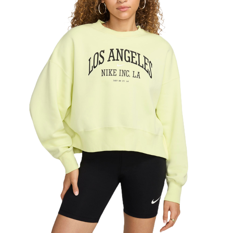 A Nike women's oversized sweater in a pastel yellow hue features bold black lettering that reads \“LOS ANGELES NIKE INC. LA\“ on the front.