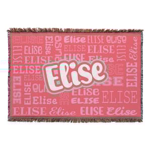 A woven blanket with fringed edges features the name \“Elise\“ in various fonts and sizes against a pink background.