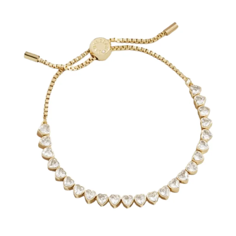 A gold-tone adjustable bracelet with heart-shaped clear stones and a sliding clasp for closure.