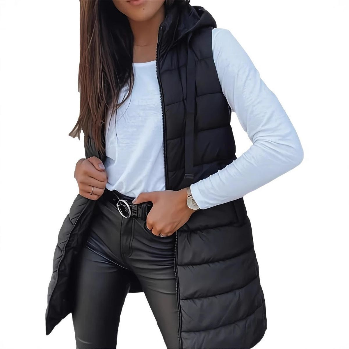 A woman is wearing a black puffer vest over a white long-sleeve shirt, black leather pants, and a belt. She has a watch on her left wrist.