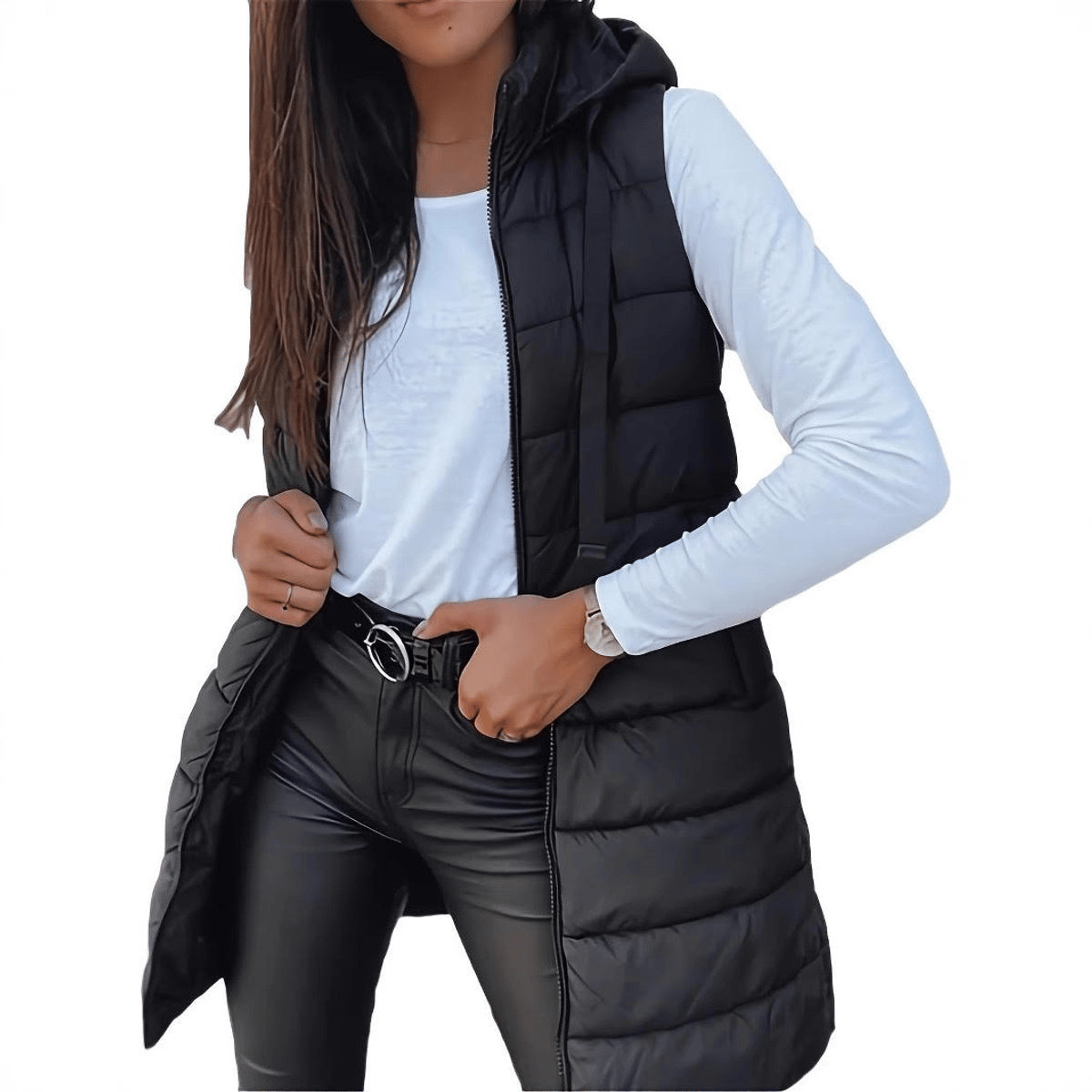 A woman is wearing a black puffer vest over a white long-sleeve shirt, black leather pants, and a belt. She has a watch on her left wrist.