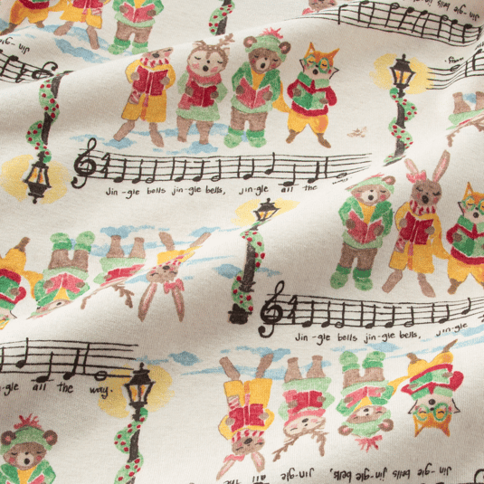 Fabric with a whimsical holiday print features animals dressed in festive outfits reading from songbooks. It includes musical notes and lyrics from \“Jingle Bells\“ along with decorated street lamps.