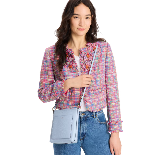 The Kate Spade Ava Swingpack is a compact crossbody bag in light blue with a front slip pocket, adjustable strap, and gold-tone hardware, ideal for carrying essentials.