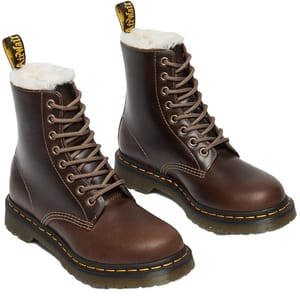 Brown Dr. Martens Serena Boots with faux fur lining, featuring 8-eye lace-up design, rugged rubber outsole, yellow stitching, and signature heel loop for easy pull-on.