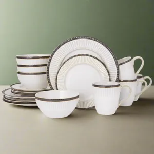 A set of white dinnerware with ribbed texture and dark rim details, including plates, bowls, and mugs.