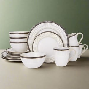 A set of white dinnerware with ribbed texture and dark rim details, including plates, bowls, and mugs.