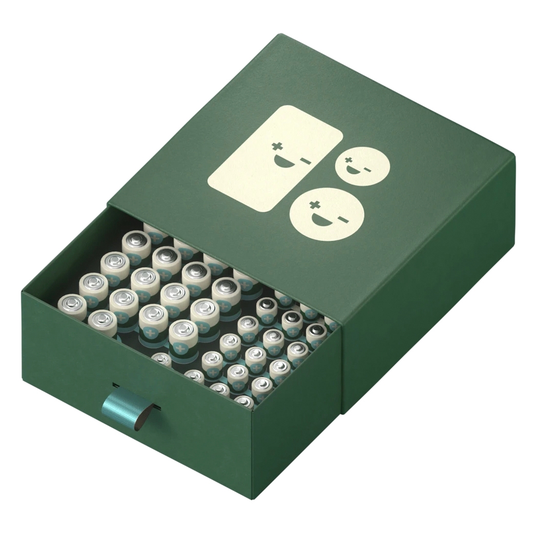 A green box with a pull-out drawer holds a collection of batteries in different sizes, featuring a playful design with smiling battery icons on the lid.