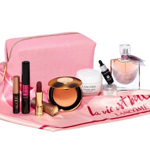 10-piece Lancôme set with pink bag includes mascara, eyeshadow stick, lipstick, bronzer compact, Hydra Zen cream, Advanced Génifique serum, La Vie Est Belle fragrance, a mini makeup remover, all on a pink cloth with \“La Vie Est Belle\“ text.