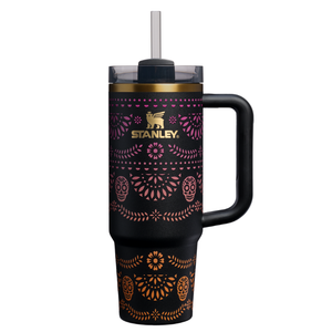 Stanley tumbler with handle and straw, featuring a black body adorned with pink and orange decorative patterns, including sugar skull motifs.