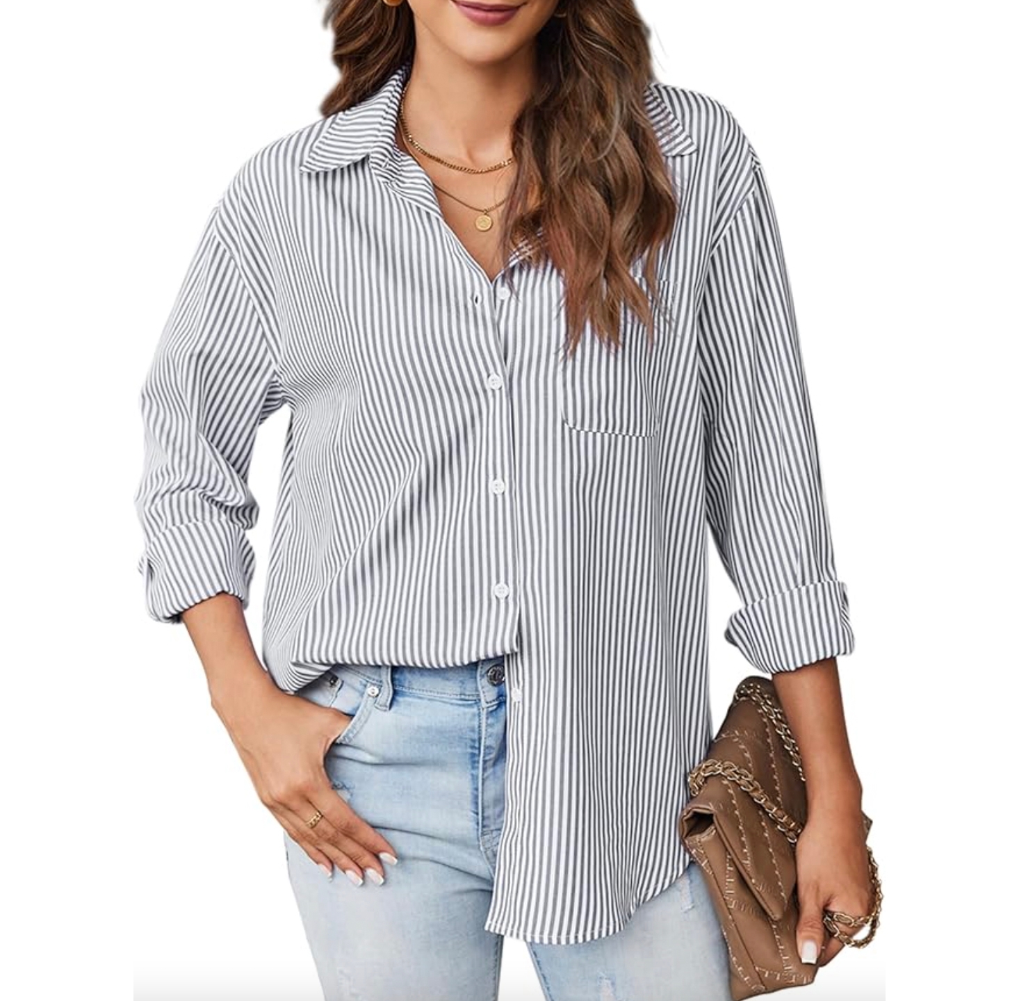A woman is wearing a black and white striped, long-sleeve button-down shirt with a front pocket. The shirt is paired with light blue jeans, a necklace, and a brown handbag with chain detailing.