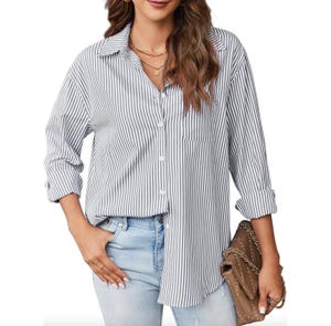 A woman is wearing a black and white striped, long-sleeve button-down shirt with a front pocket. The shirt is paired with light blue jeans, a necklace, and a brown handbag with chain detailing.