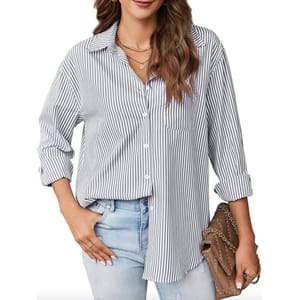 A woman is wearing a black and white striped, long-sleeve button-down shirt with a front pocket. The shirt is paired with light blue jeans, a necklace, and a brown handbag with chain detailing.