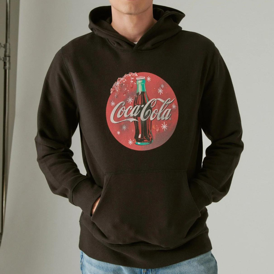 A person is wearing a brown hoodie with a Coca-Cola logo on the front.